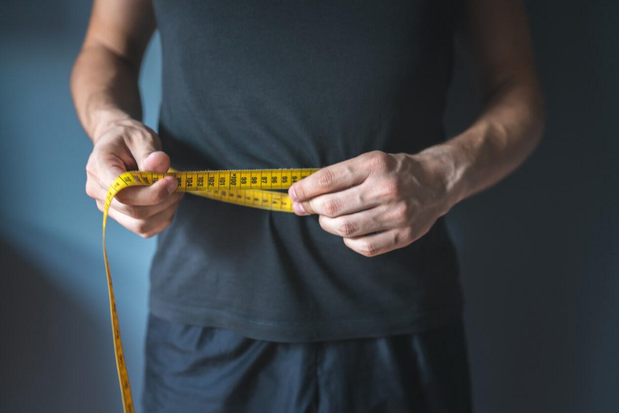 Slim man measuring his waist.