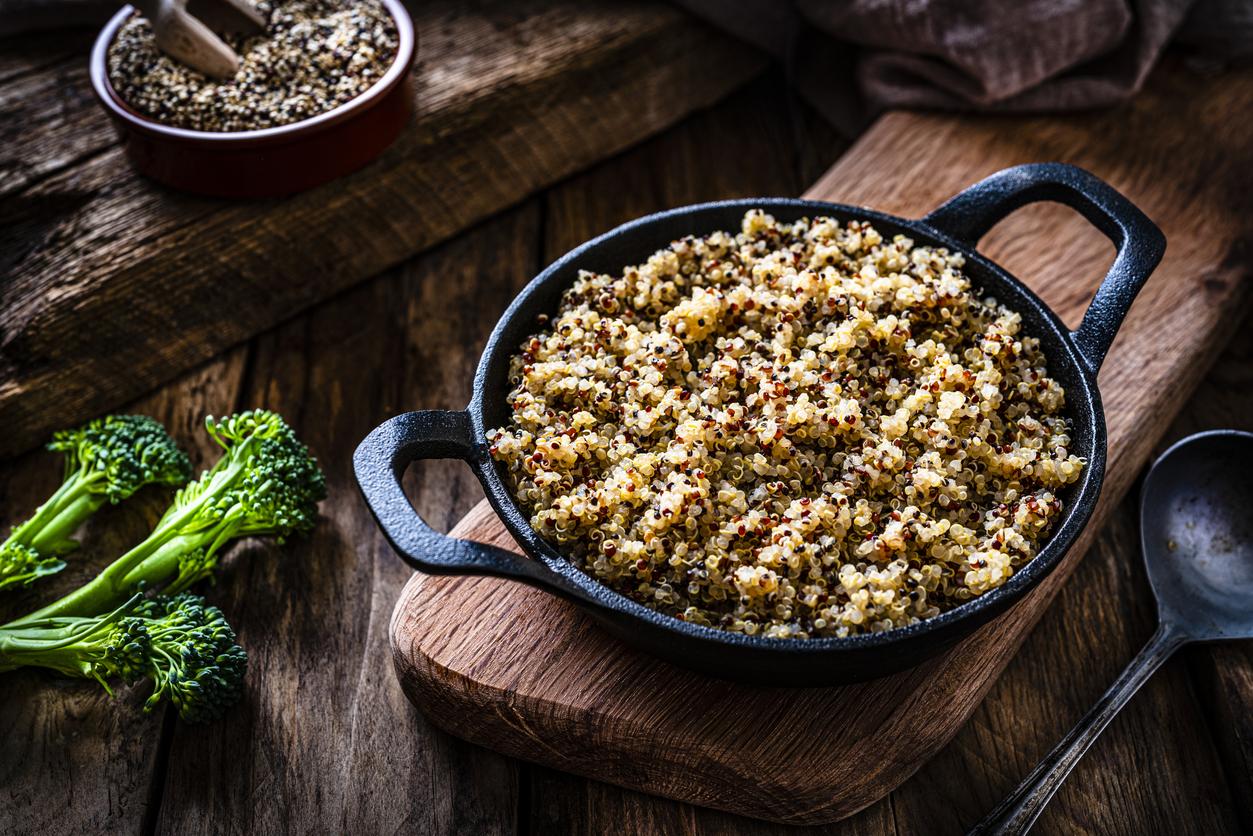 Vegan food: cooked quinoa in a cast iron pan shot on rustic wooden table. Predominant colors are brown and green. High resolution 42Mp studio digital capture taken with SONY A7rII and Zeiss Batis 40mm F2.0 CF lens
