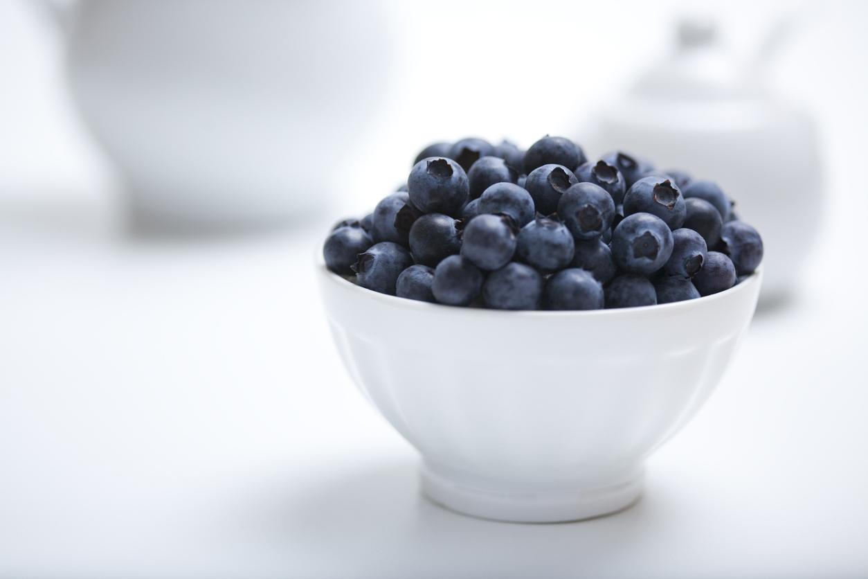 Heap of fresh blueberries in a white bowl with white objects in a white background with available copy space.