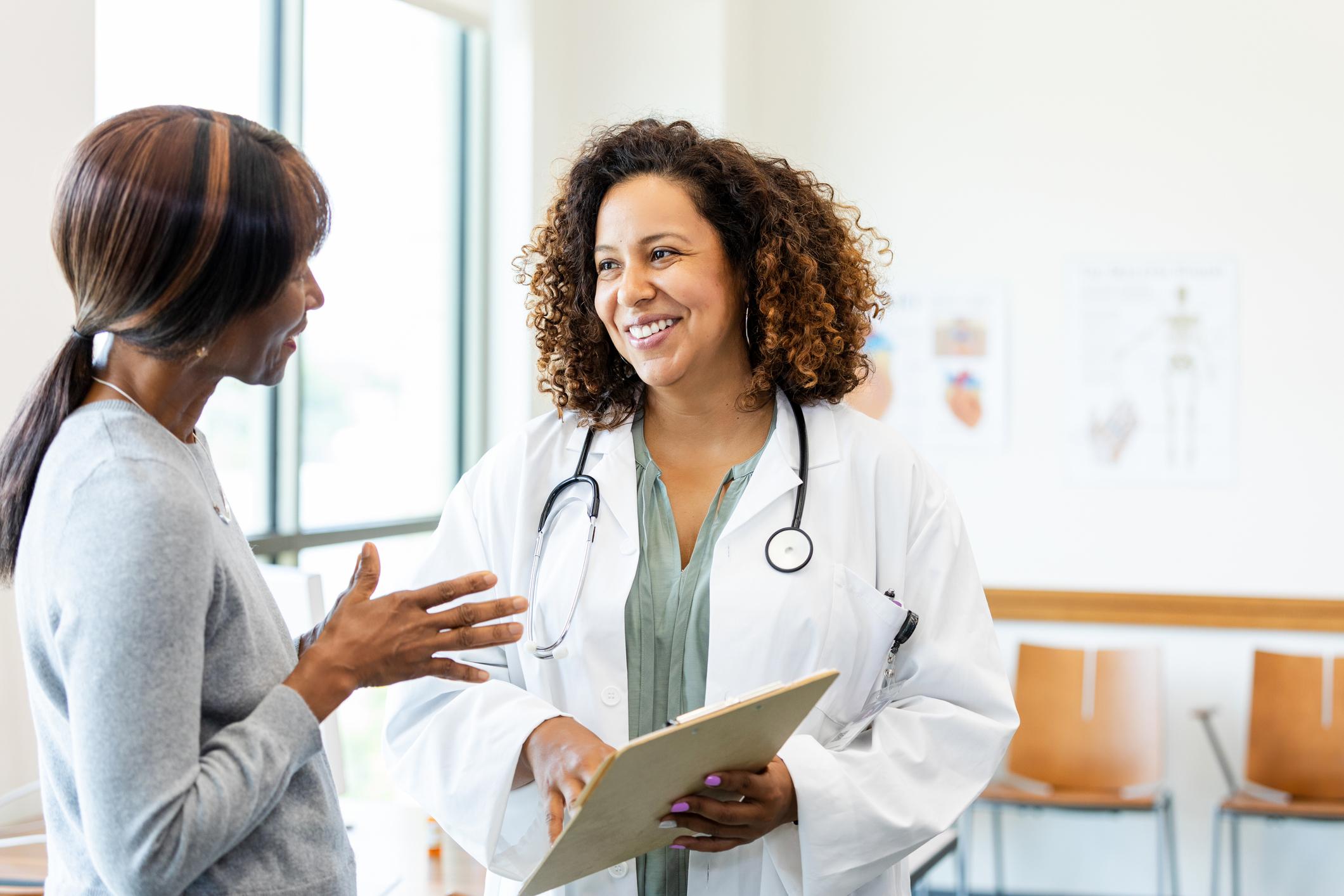 Female doctor and patient talking; healthcare and medicine;  indoors;  smiling;  communication.