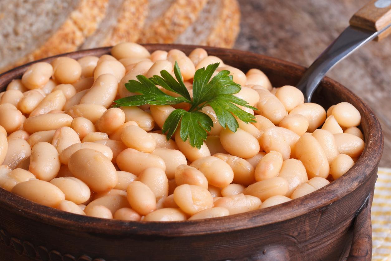 white kidney beans in a brown pot macro and bread on the table horizontal