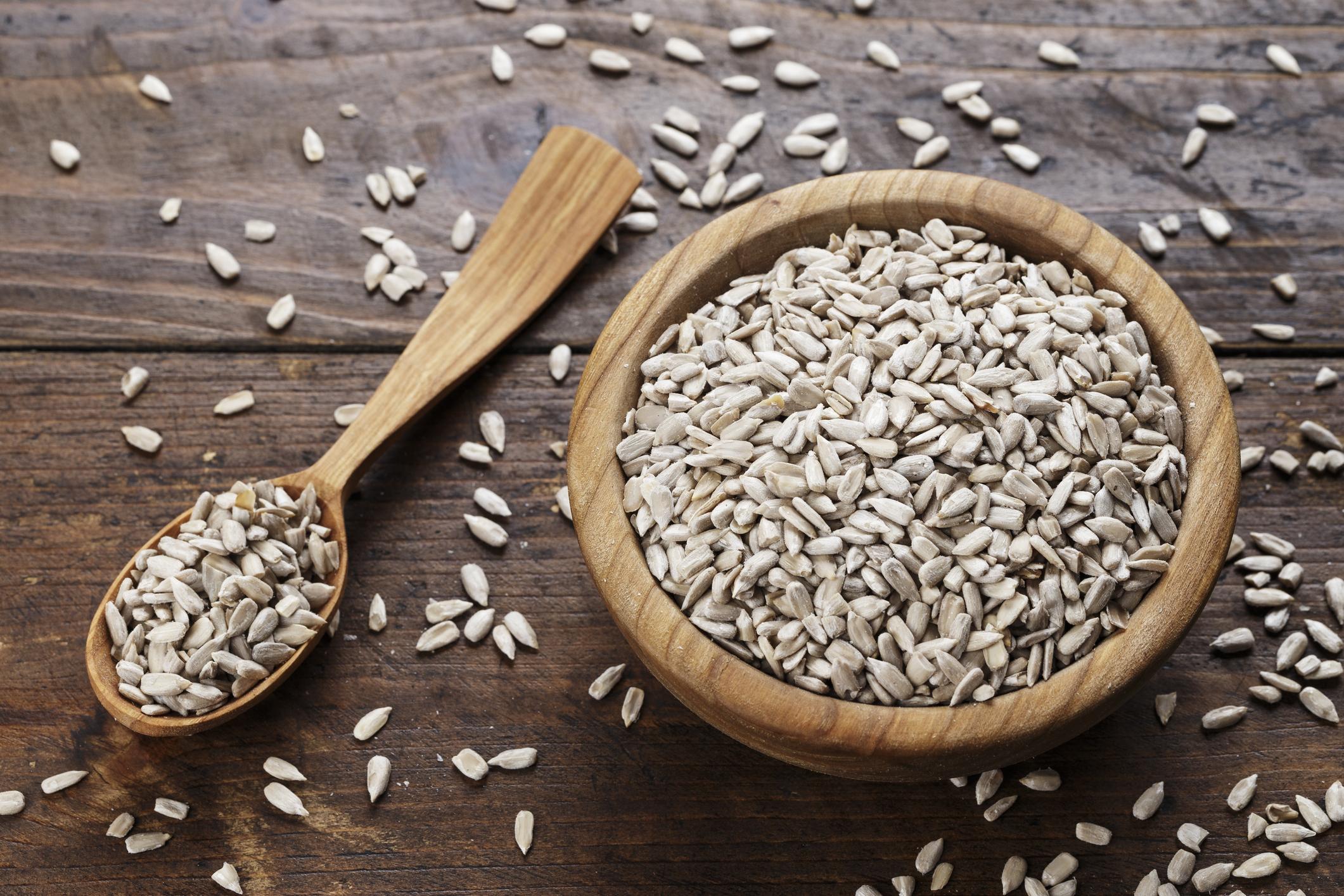 Peeled sunflower seeds on a wooden background in a plate. place for text